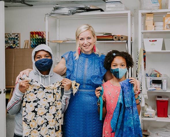 Skye Barker Maa poses with two fashion students holding garments at Factory Five Five.