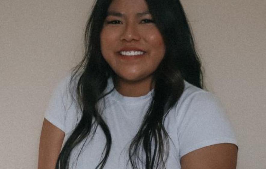 Headshot of smiliing woman with long black hair and a white shirt.