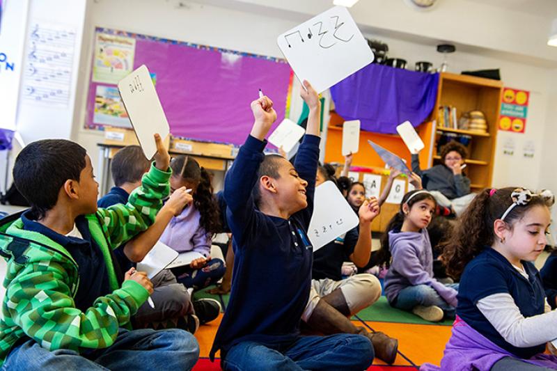 Kids holding up whiteboards with music notes on them