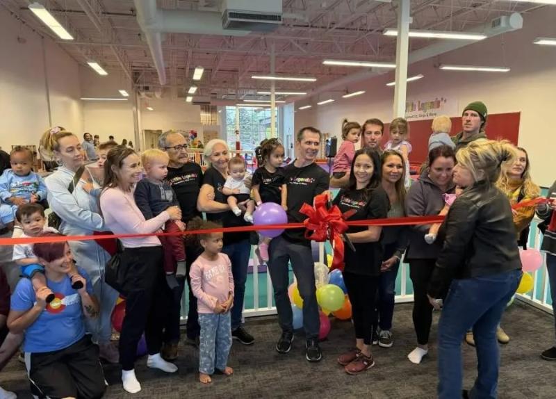 Surrounded by supporters, Jessica Lopez cuts a big red ribbon on her new business, Little Legends Athletics.