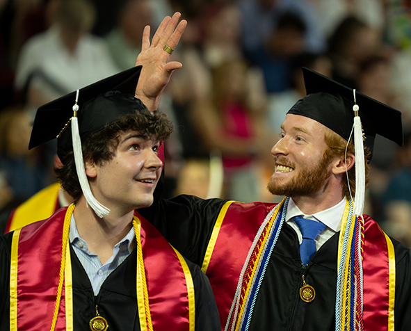 Two students in graduation regalia at 2024 Undergraduate Commencement